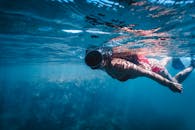 A woman wearing a bikini snorkeling in the clear blue sea of Bahia, Brazil, enjoying underwater exploration.