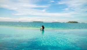 A woman relaxes in an infinity pool with a stunning ocean view.