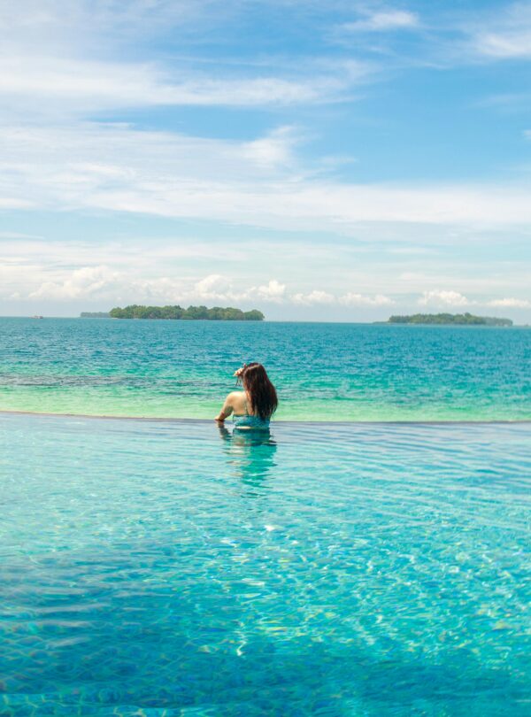 A woman relaxes in an infinity pool with a stunning ocean view.